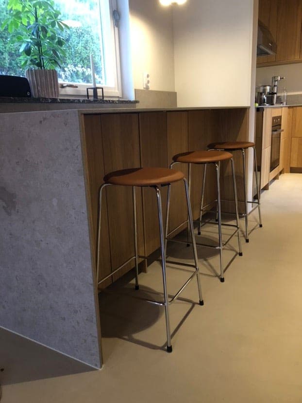 Microcementgolv i ett verkligt kök med köksö och barstolar
